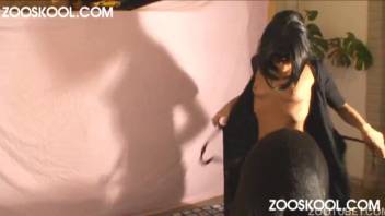 Sophisticated slim dark-haired woman engages in intercourse with a black canine